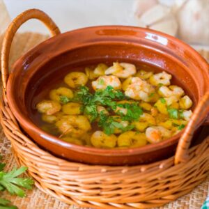 Gambas al ajillo servidas en cazuela de barro, con ajo dorado y aceite de oliva caliente