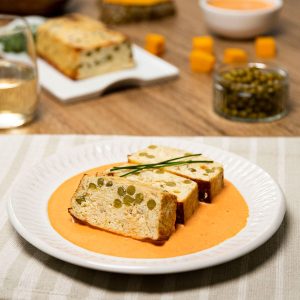 Pastel de calabaza y guisantes servido sobre salsa.