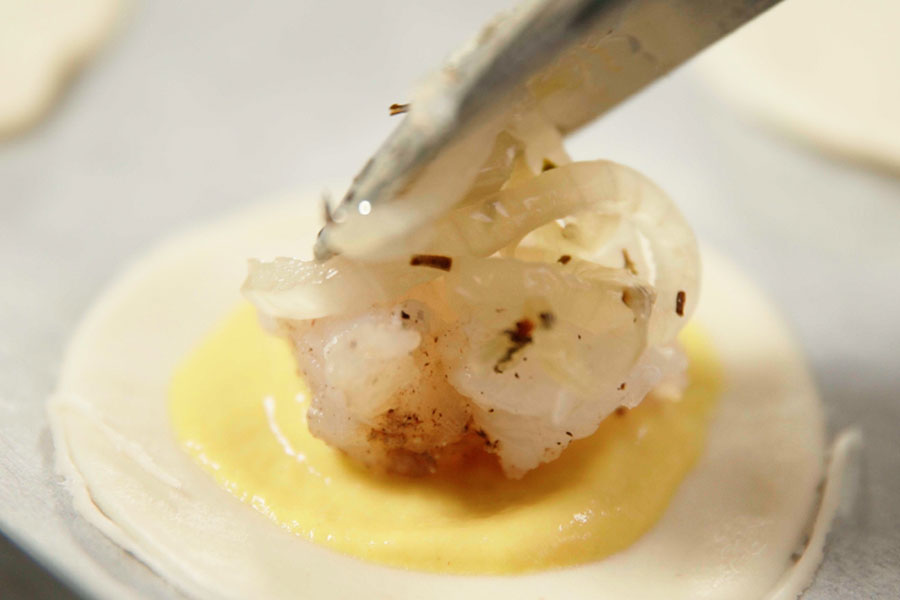 Receta casera de Mini empanadas de bacalao. Cortamos 2 láminas de hojaldre en porciones. Sobre cada una de ellas, añadimos una base de mostaza, bacalao salpimentado y cortado en dados, cebolla pochada y un trozo de queso brie. Cerramos con otra porción de hojaldre y sellamos con ayuda de un tenedor.