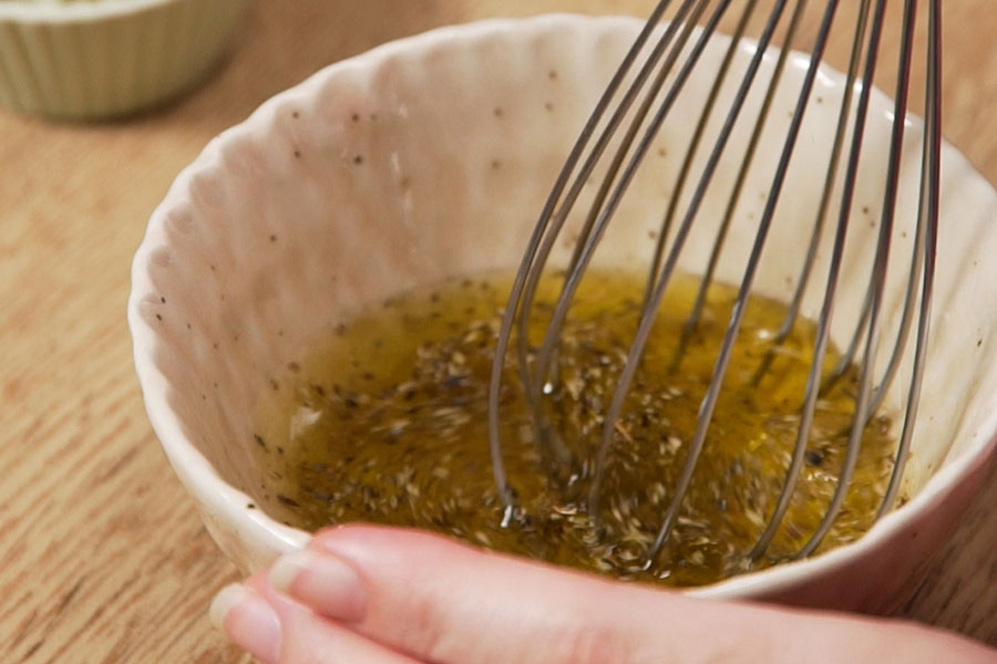 Receta casera. Ensalada griega de berenjena. Preparamos una vinagreta con AOVE Excelentum La Masía, vinagre, sal, pimienta y orégano. Mezclamos y reservamos