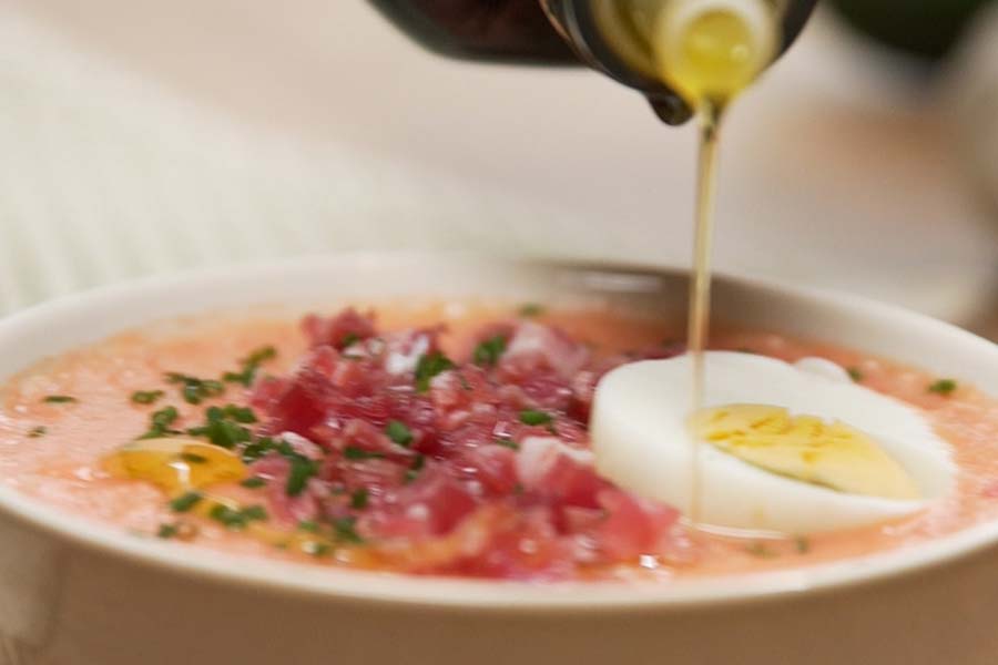 Receta casera de Salmorejo de calabacín sin gluten. Servimos el salmorejo y lo aderezamos con huevo duro picado, taquitos de jamón, cebollino picado y un poco más de aceite de oliva virgen extra Olivar Tradicional La Masía