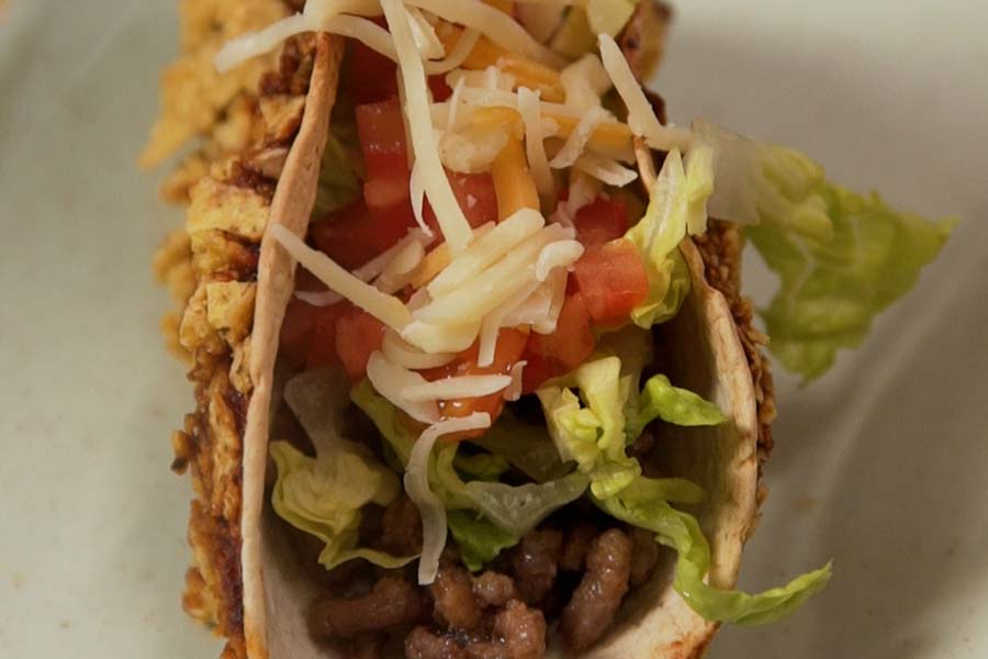 Receta casera de Tacos crujientes de carne. Montamos los tacos añadiendo carne picada, lechuga y tomate picados y mozzarella rallada.