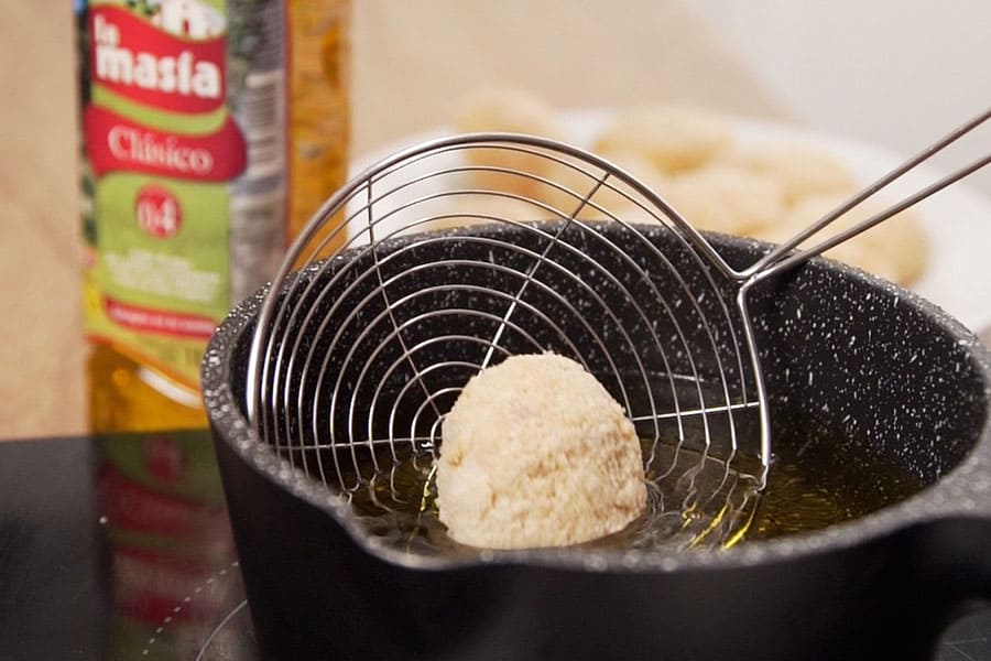 Receta casera de Croquetas de huevos rellenos de jamón. Rebozamos los huevos y los freímos en abundante aceite de oliva Clásico La Masía