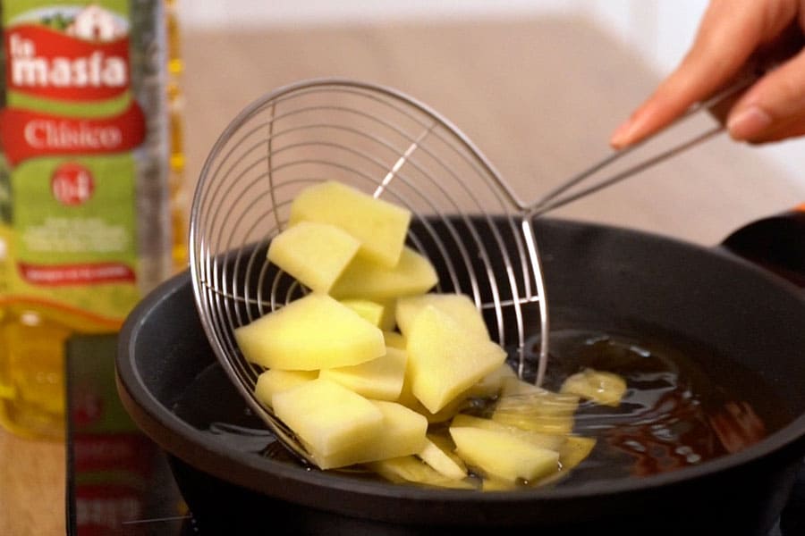Receta casera de Tortilla de patatas carbonara. Freímos las patatas en aceite de oliva Clásico La Masía.