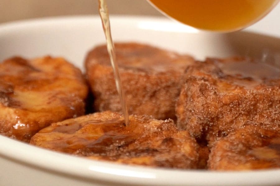 Receta casera de torrijas rellenas de flan. Pasamos por leche y huevo y freímos las torrijas en aceite de semillas Masiasol. Rebozamos en azúcar y canela y añadimos el almíbar.