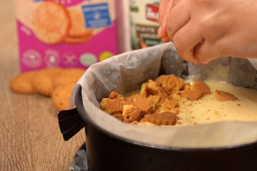 Receta casera de Cheesecake de natillas. Pasamos la mezcla de queso al molde, añadimos galletas y reservamos en frío