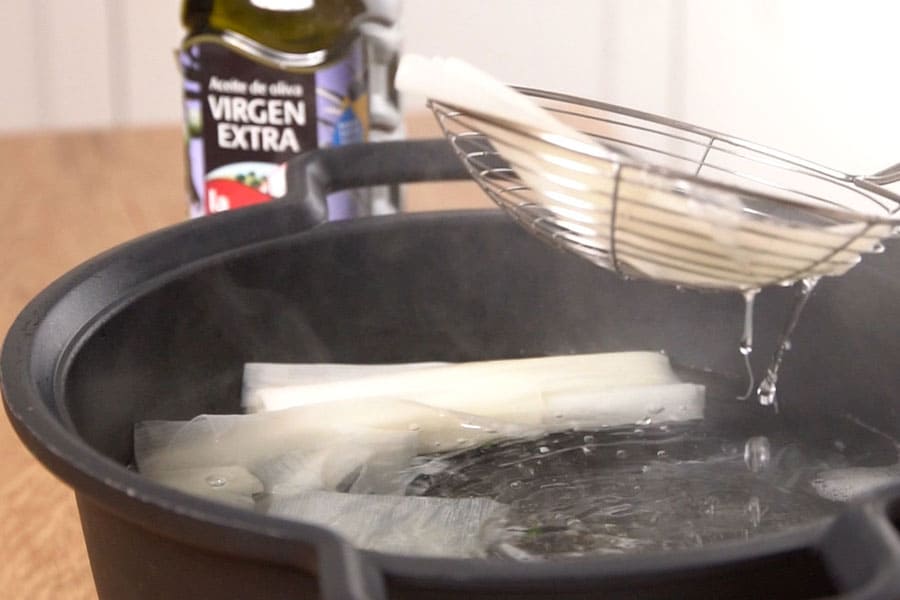 Receta casera de Canelones de puerro rellenos de merluza y gambas. Escaldamos el puerro y lo reservamos