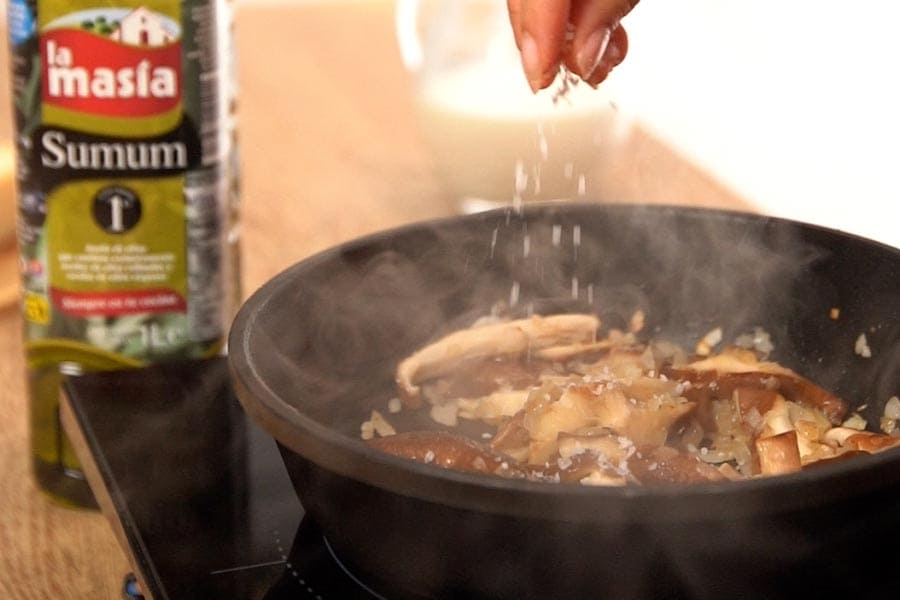Pollo y setas marcándose en la sartén con aceite de oliva sumum.