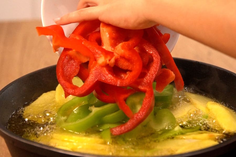 Receta Casera de Bacalao con patatas y cebolla caramelizada. Freímos patatas y pimientos rojo y verde en Aceite de oliva clásico La Masía.