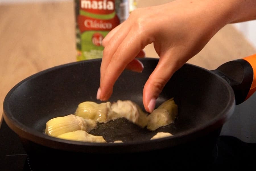 Receta casera de Alcachofas con jamón y huevo de codorniz. Marcamos las alcachofas en una sartén con aceite de oliva Clásico La Masía