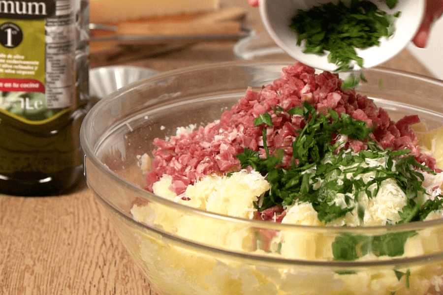 Receta casera de Nidos de patata y champiñones. Preparamos una masa con patata cocida, queso parmesano rallado, jamón serrano, perejil, sal y pimienta. Damos forma a las cestas
